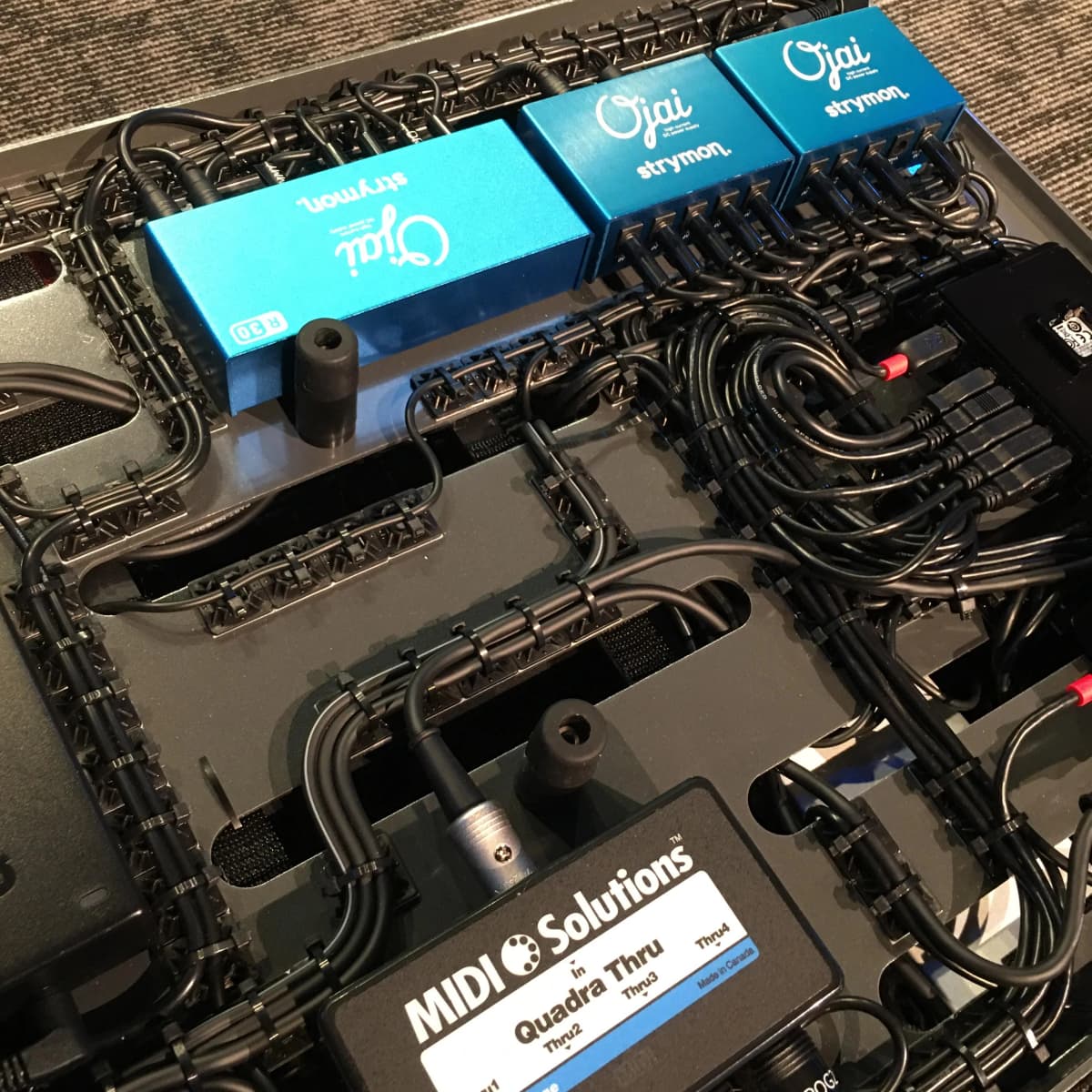 Underside of a Rig Doctor pedalboard showing cut-to-length cable runs and isolated power